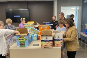 a group of people standing around a table with boxes of food