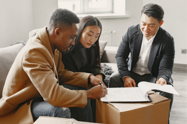 photo of homebuyers signing closing contract with their REALTOR®